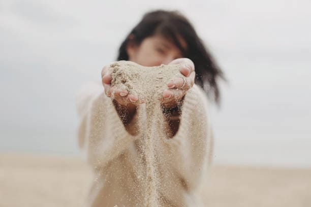 Woman hands holding sand on beach
