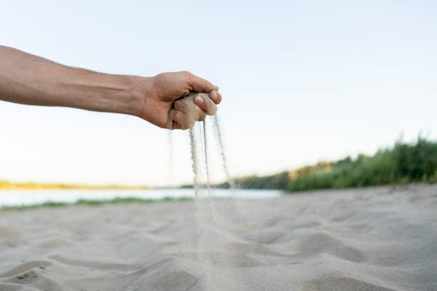hand holding sand on beach