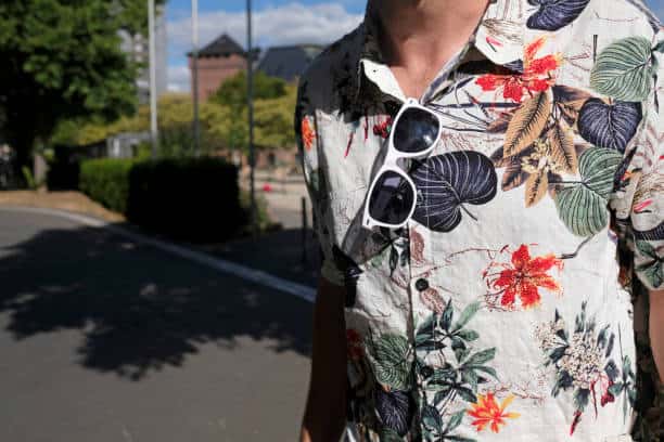 Man wearing a Hawaiian shirt with a pair of white sunglasses tucked in