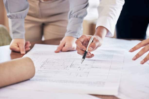 architect drawing a blueprint or planning a real estate building or development in an office.